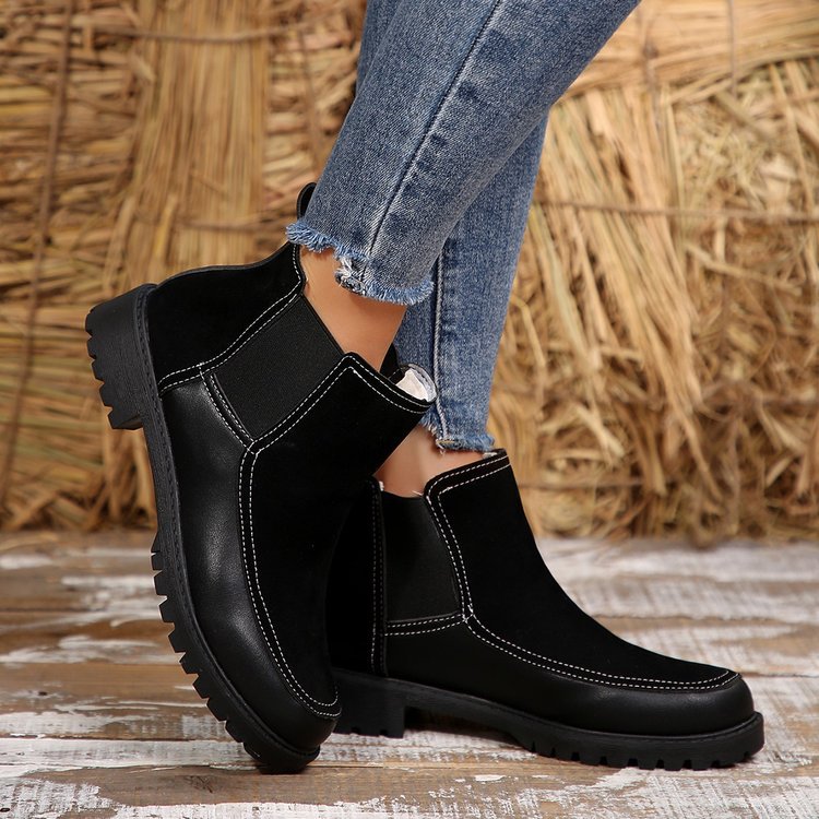 Black boots worn with blue jeans against a rustic background