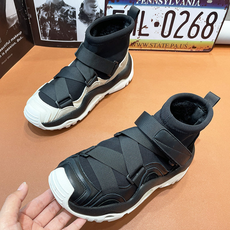 Black and white high-top sneakers with straps on a brown surface, with a Pennsylvania license plate in the background.