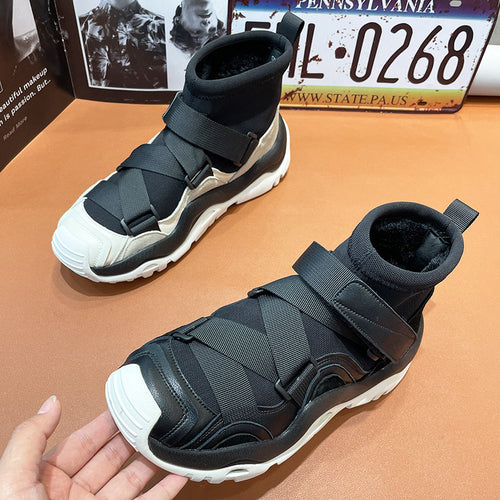 Black and white high-top sneakers with straps on a brown surface, with a Pennsylvania license plate in the background.