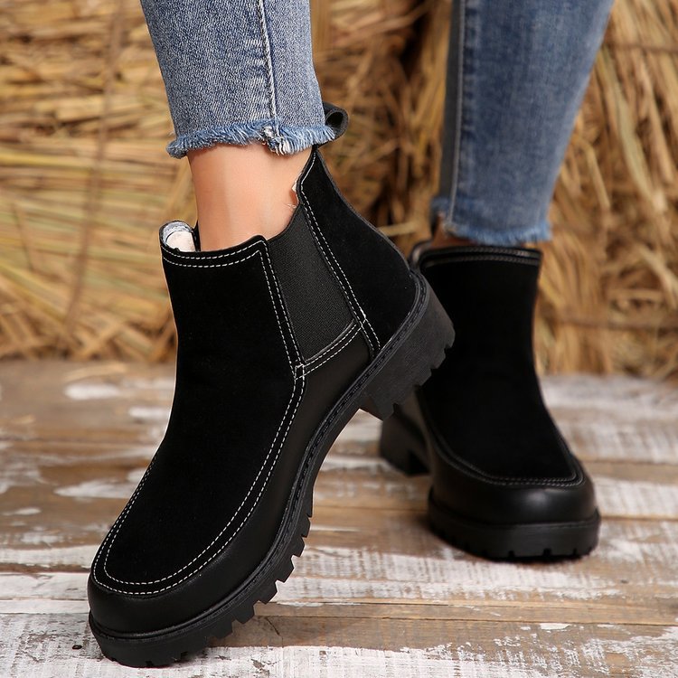 Black boots worn with blue jeans against a rustic background