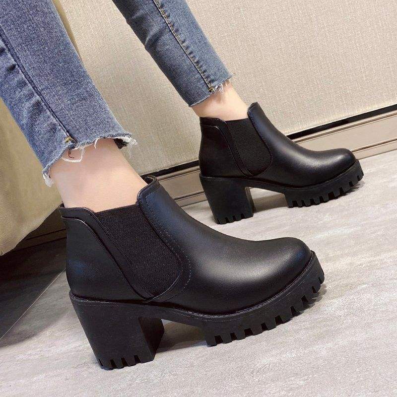 Black chunky-heeled ankle boots worn with jeans on a neutral background