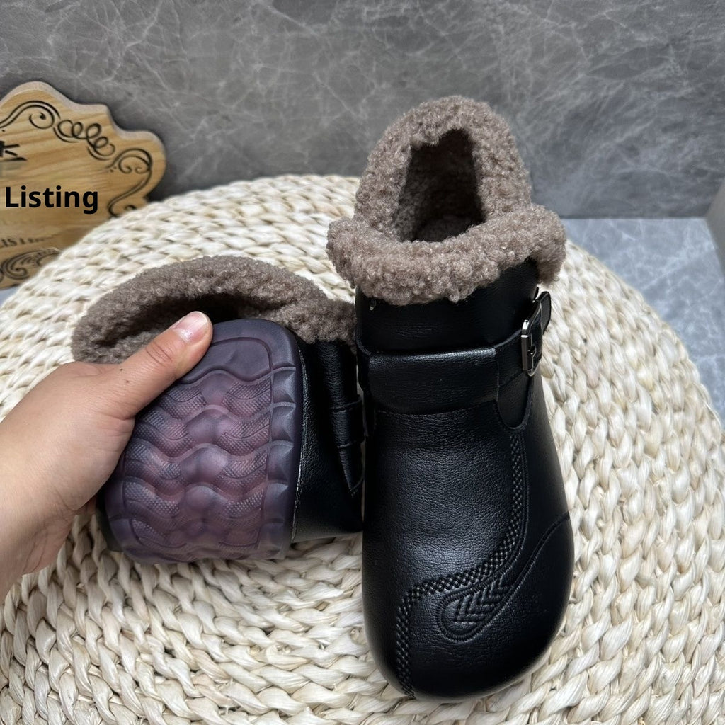 Black leather boot with fur lining held by a hand on a textured surface