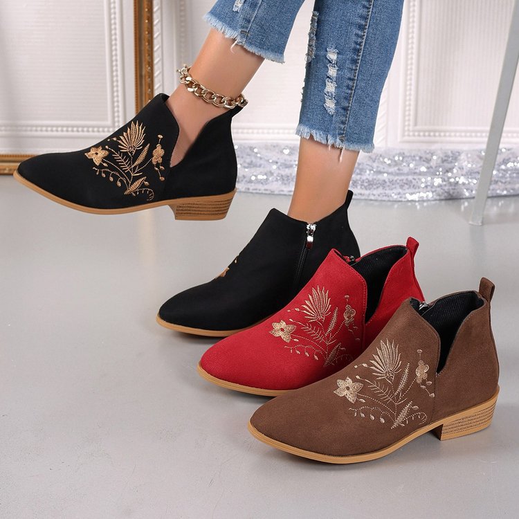 Black, red, and brown ankle boots with floral embroidery on a light gray floor.
