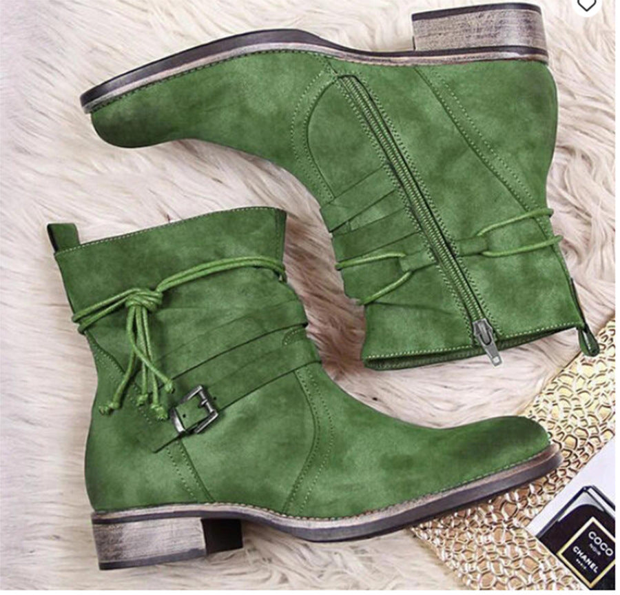 Green suede boots with zippers and laces on a textured surface