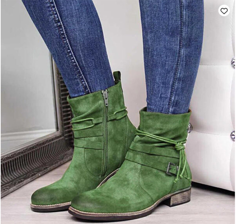 Green suede boots worn with blue jeans on a neutral background