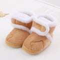 Pair of tan baby booties with white fur trim on a light background