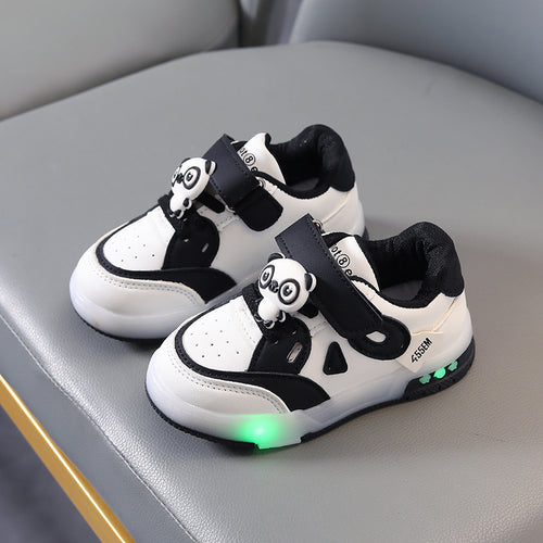 Pair of black and white children's sneakers with panda decorations on a gray surface.