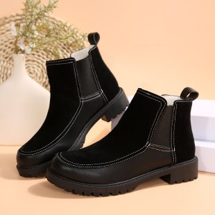 Pair of black leather boots on a beige background