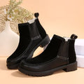 Pair of black leather boots on a beige background