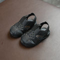 Pair of black sandals on a brown leather surface