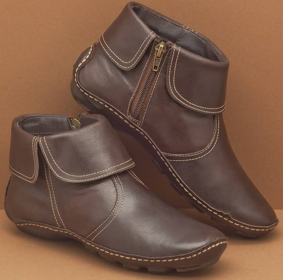Pair of brown leather boots with zippers on a brown background