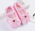 Pair of pink baby shoes with bows on a white background