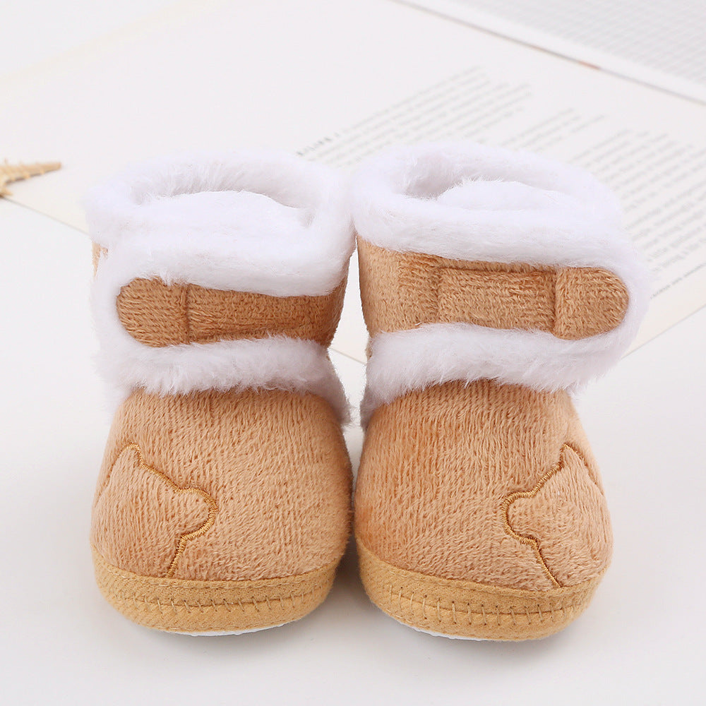 Pair of tan baby booties with white fur trim on a light background