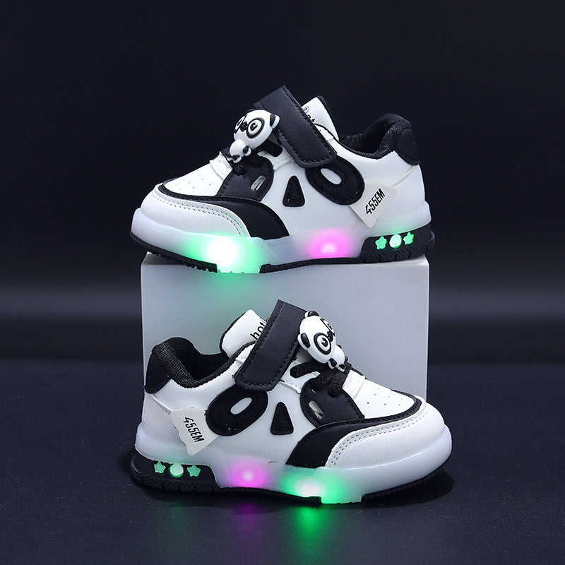 Pair of white and black children's sneakers with colorful LED lights on a gray background