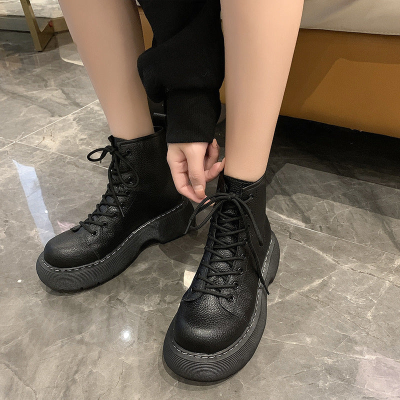 Person wearing black leather boots on a marble floor