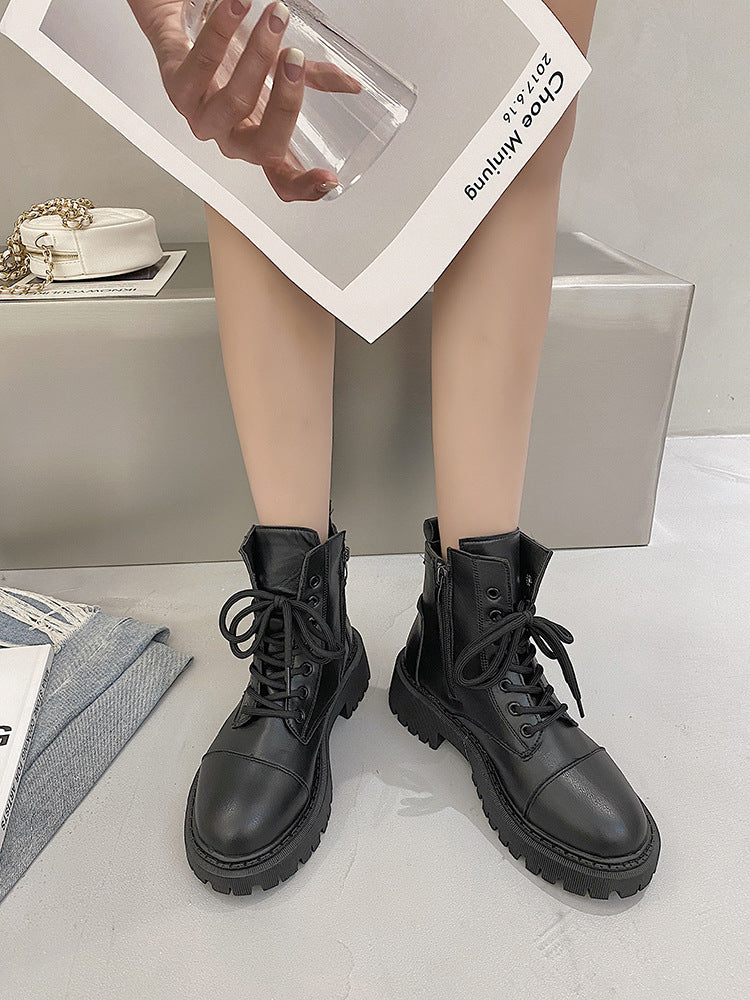 Person wearing black leather boots with a neutral background