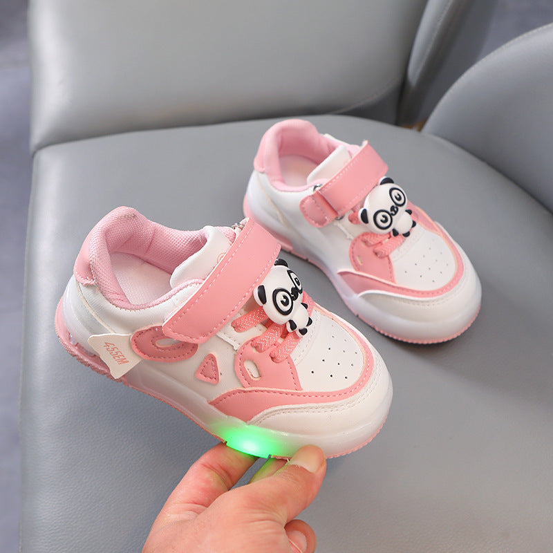 Pink and white children's shoes with panda design on a gray surface