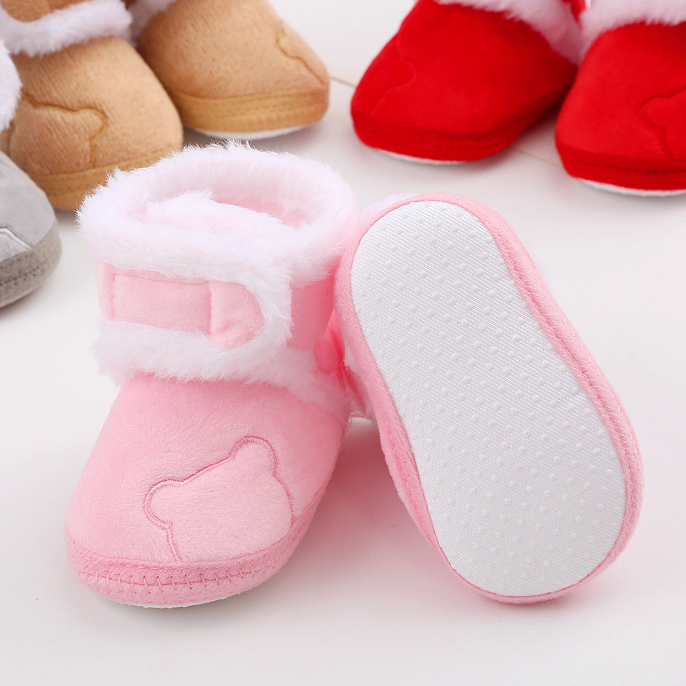 Pink baby booties with white soles on a light background