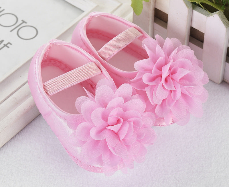 Pink baby shoes with flowers on a light background