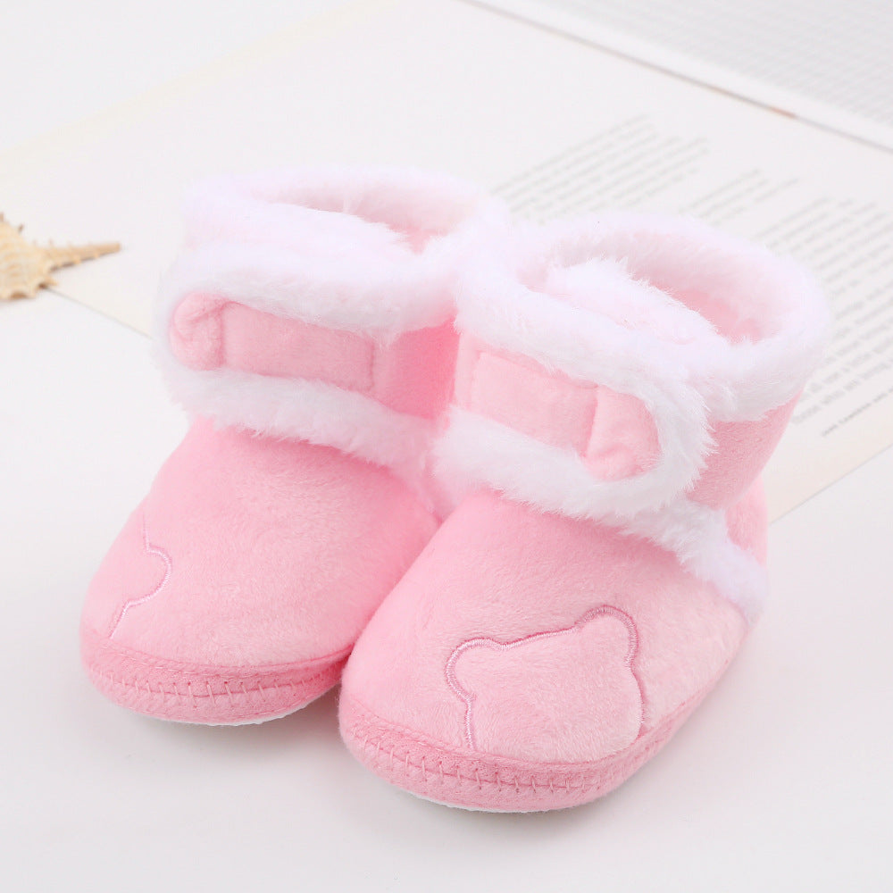 Pink baby shoes with white fur trim on a light background