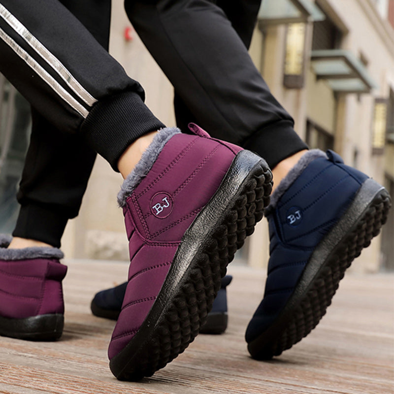Purple and blue winter boots worn on a wooden floor with a blurred background