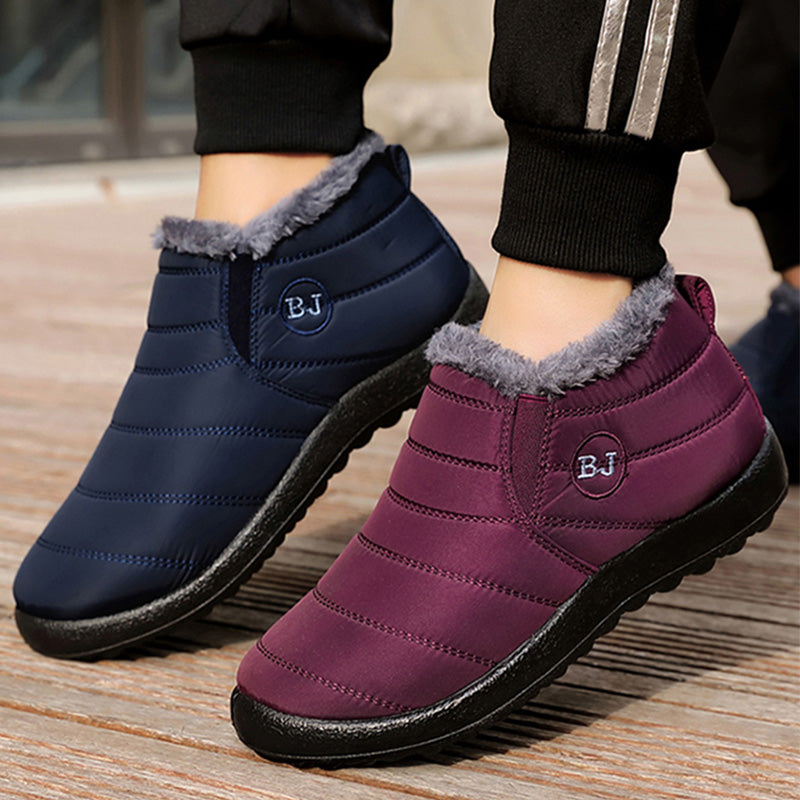 Purple and navy winter shoes with gray fur lining on a wooden floor.