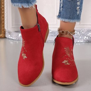 Red ankle boots with floral embroidery worn with denim jeans on a light background