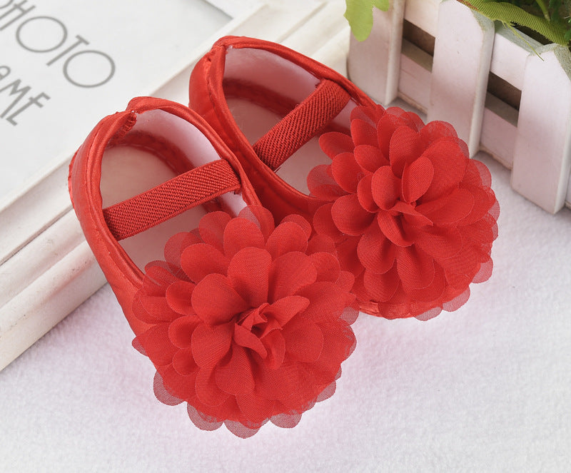 Red baby sandals with floral designs on a light background