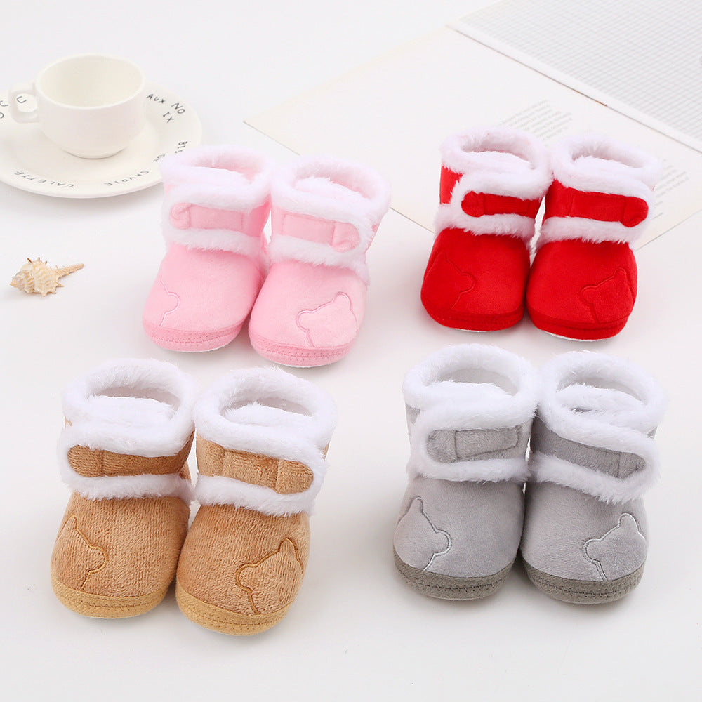Set of four pairs of baby booties in pink, red, brown, and gray on a white surface.