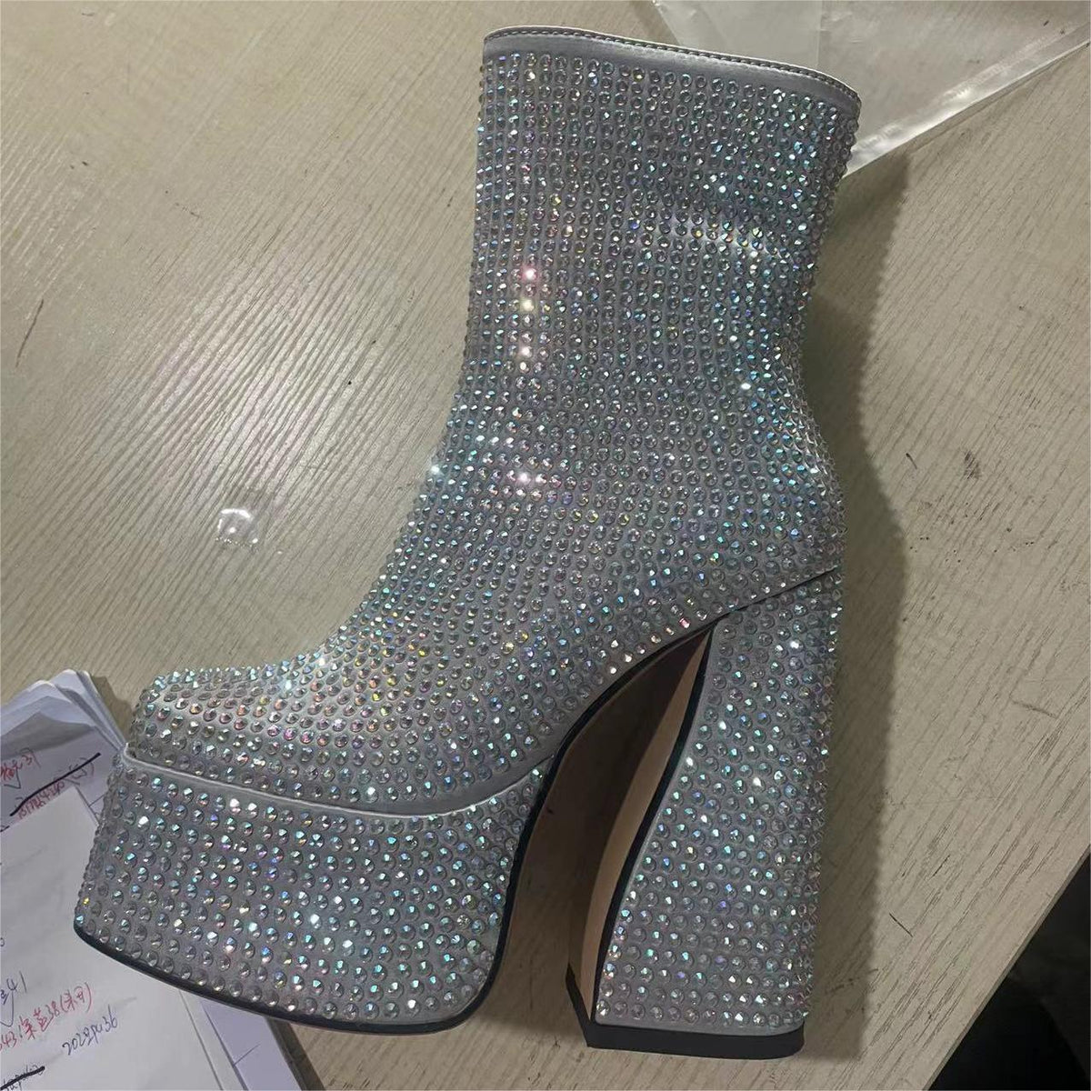 Silver glittery high-heeled boot on a wooden surface