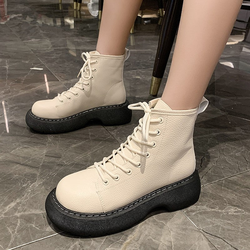 White platform boots with black soles on a tiled floor.